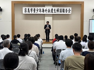 報告会であいさつする様子